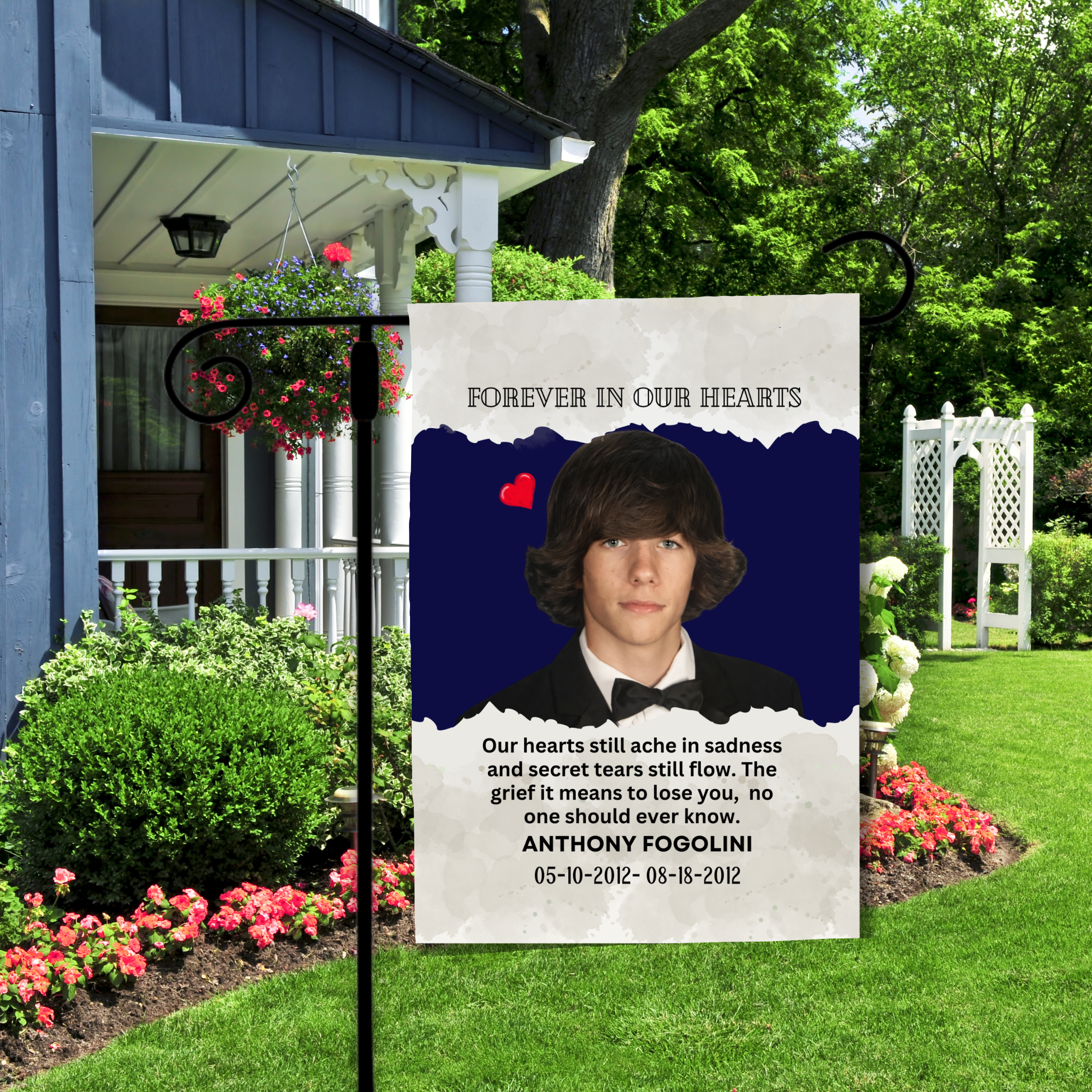 Memorial sign with a photo of a young man and text in a garden setting.