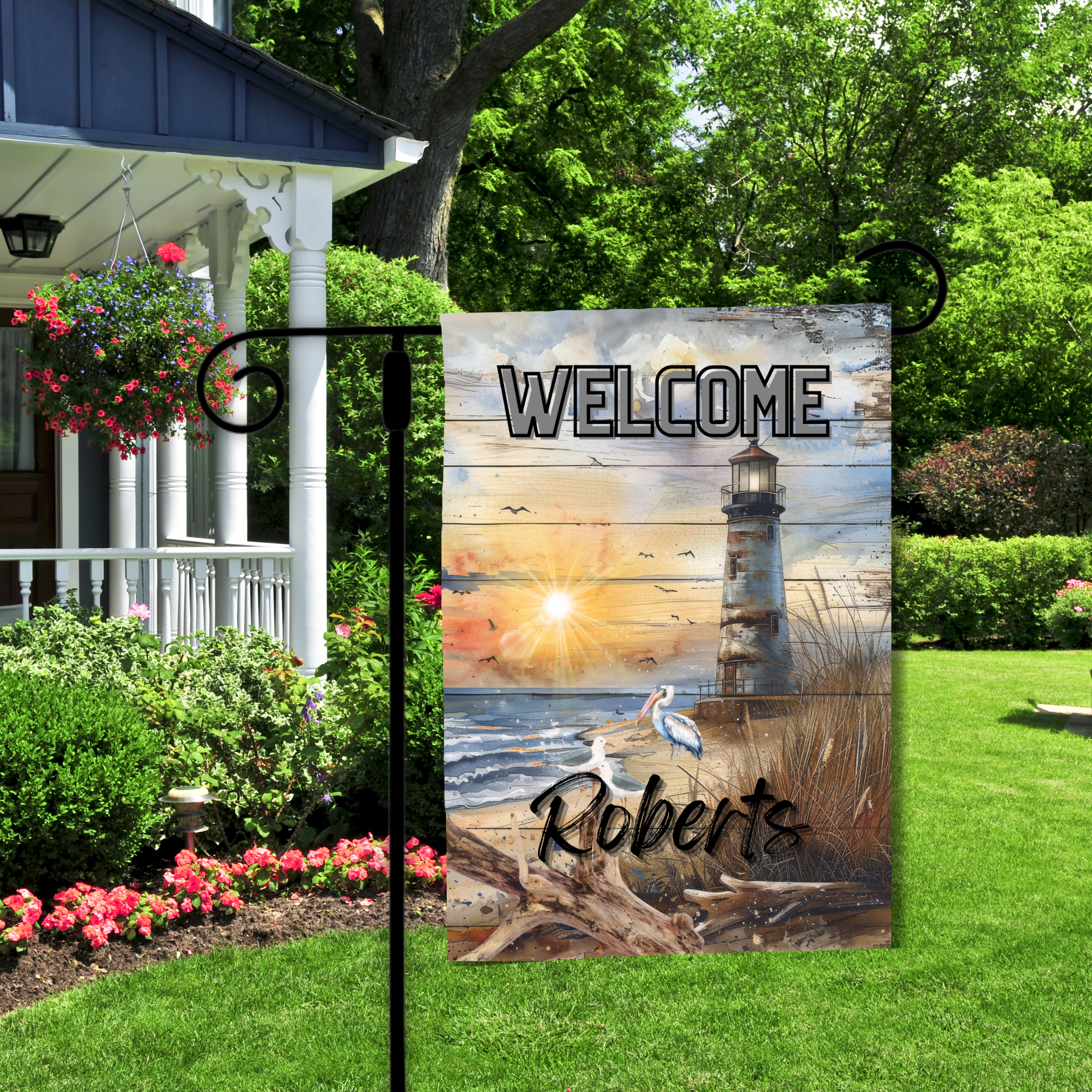 Decorative garden flag with lighthouse design and 'Welcome Roberts' text in a garden setting.