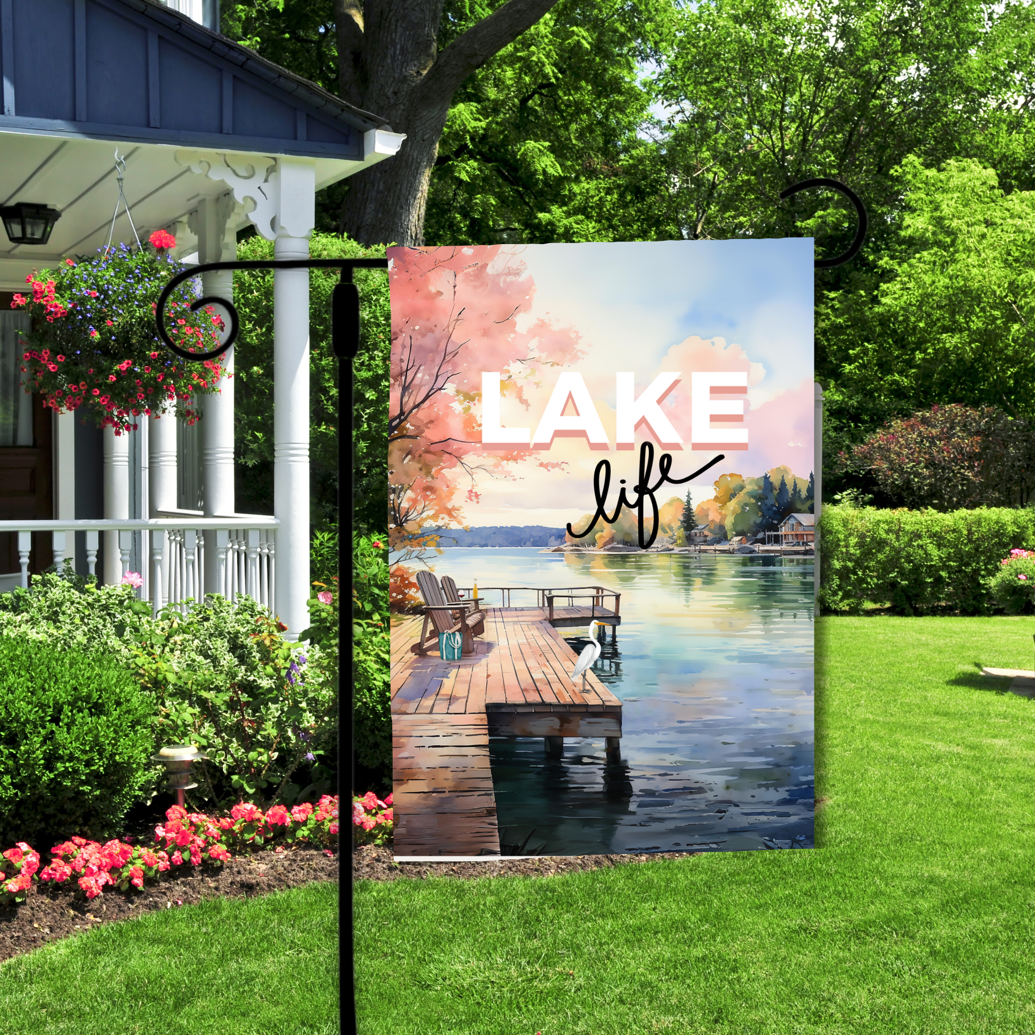 Decorative flag with 'Lake Life' text and a dock scene in a garden setting.