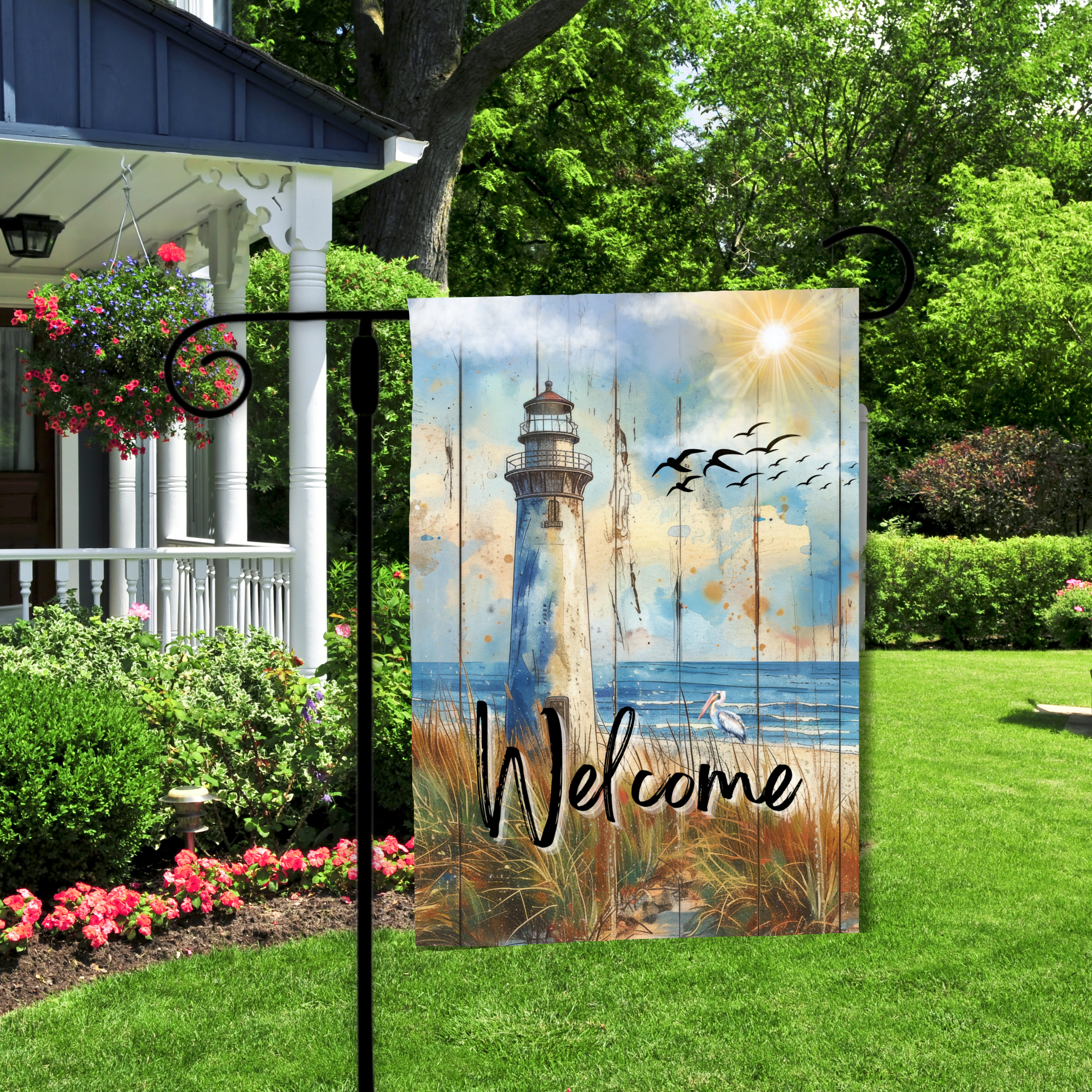 Decorative garden flag with a lighthouse design and 'Welcome' text, displayed outdoors.